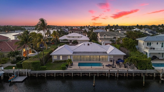 7 Inlet Cay Dr, Ocean Ridge, FL 33435 - back of house at dusk with a water view, a patio area, a residential view, and a fenced in pool