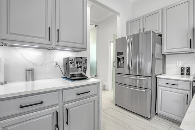 8086 Bautista Way, Palm Beach Gardens, FL 33418 - kitchen featuring decorative backsplash, gray cabinets, crown molding, light stone countertops, and stainless steel fridge with ice dispenser