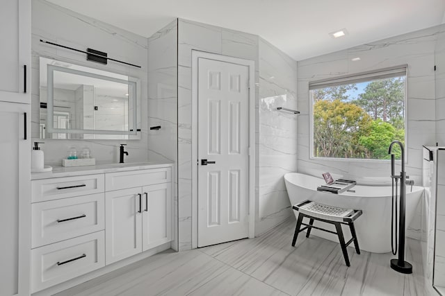 8086 Bautista Way, Palm Beach Gardens, FL 33418 - bathroom featuring a freestanding tub, tile walls, and vanity