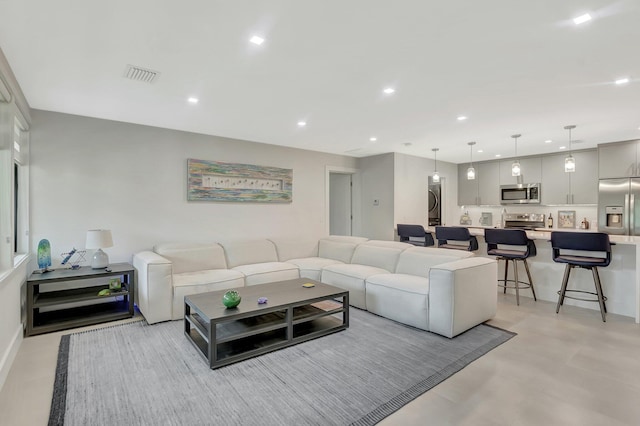 living area featuring concrete flooring, visible vents, recessed lighting, and stacked washer / dryer