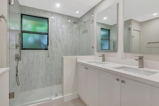 full bath featuring double vanity, a sink, and a shower stall