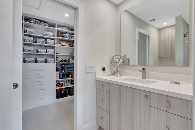 bathroom featuring visible vents, recessed lighting, vanity, and a walk in closet