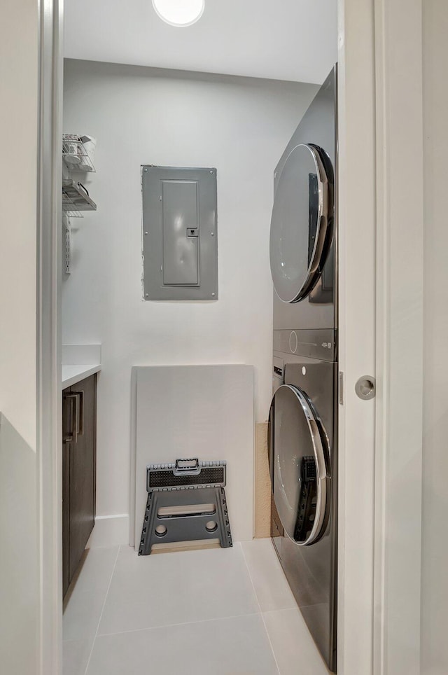 laundry room featuring stacked washer and clothes dryer, tile patterned flooring, laundry area, and electric panel