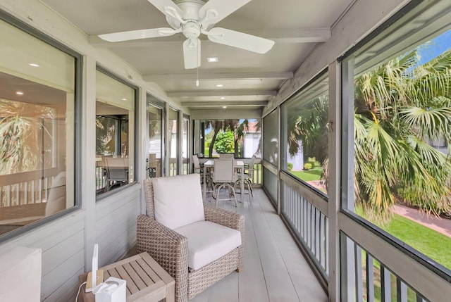 sunroom with outdoor dining space, a ceiling fan, and beam ceiling