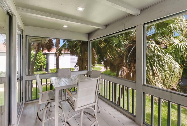 sunroom with beam ceiling and outdoor dining space