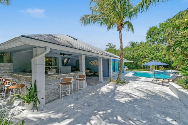 view of patio featuring a pool with connected hot tub, a ceiling fan, and outdoor dry bar