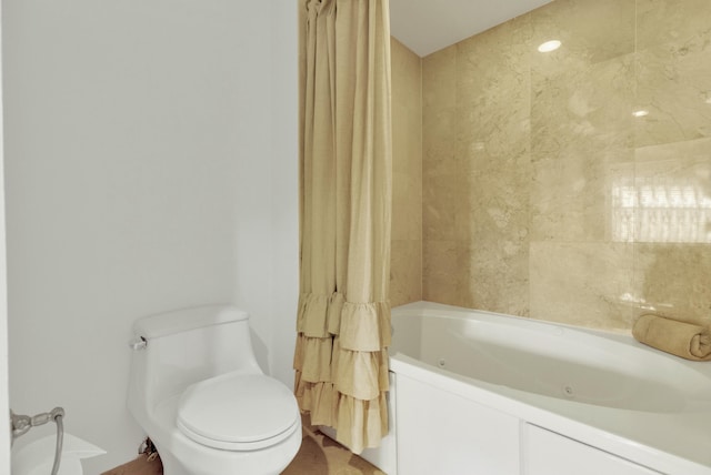 bathroom with toilet and a combined bath / shower with jetted tub