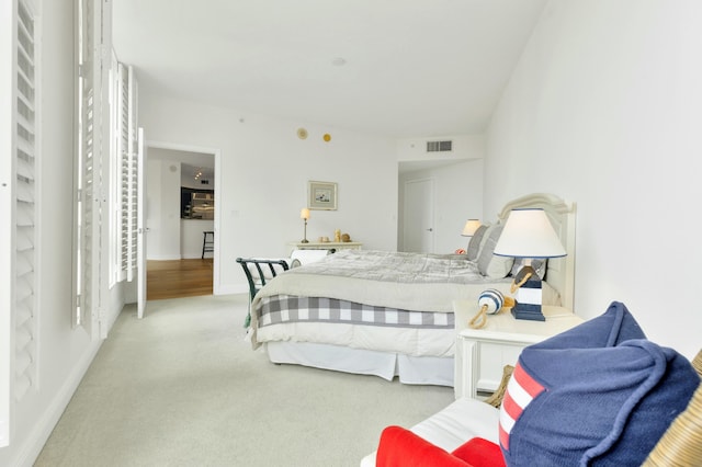 bedroom with baseboards, light colored carpet, and visible vents