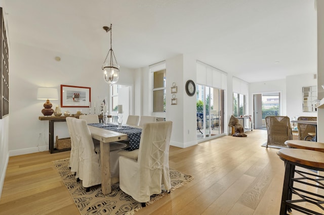 dining room with baseboards, an inviting chandelier, and light wood finished floors