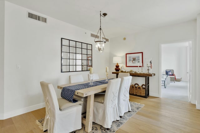 dining space with an inviting chandelier, light wood-type flooring, baseboards, and visible vents