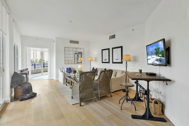 living room with light wood-style flooring, baseboards, and visible vents