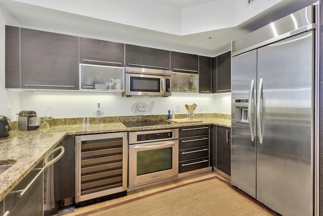 kitchen with modern cabinets, wine cooler, light stone countertops, and appliances with stainless steel finishes