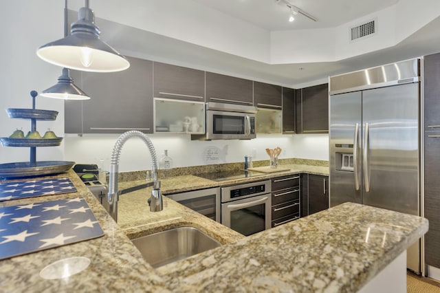 kitchen with visible vents, light stone countertops, appliances with stainless steel finishes, a sink, and pendant lighting