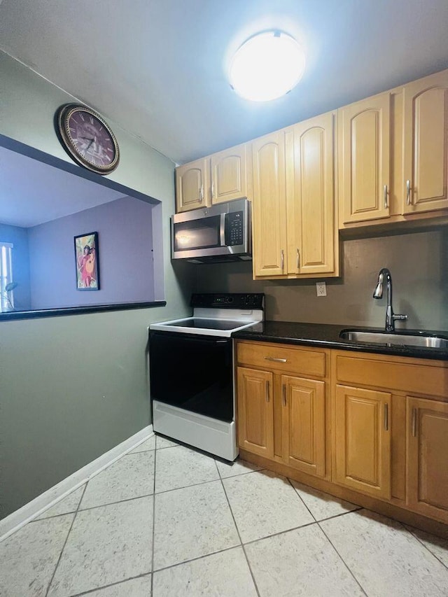 kitchen featuring dark countertops, a sink, light tile patterned floors, electric range oven, and stainless steel microwave