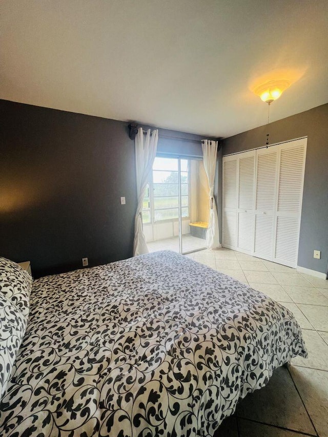 bedroom with baseboards, access to outside, tile patterned floors, and a closet