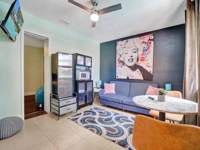 living room with baseboards, visible vents, light tile patterned floors, and a ceiling fan