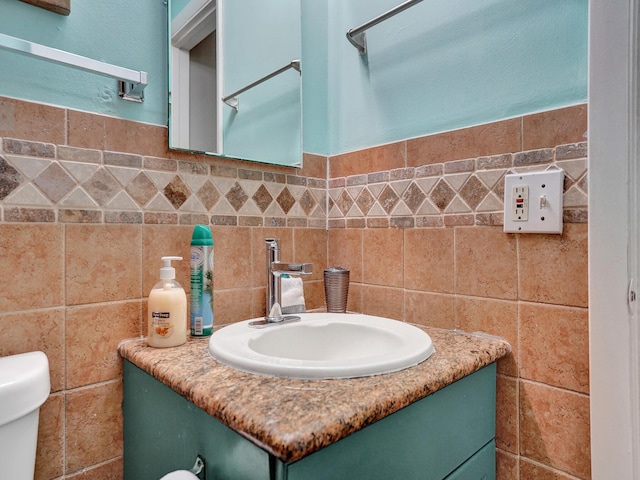 bathroom with a wainscoted wall, tile walls, toilet, and vanity