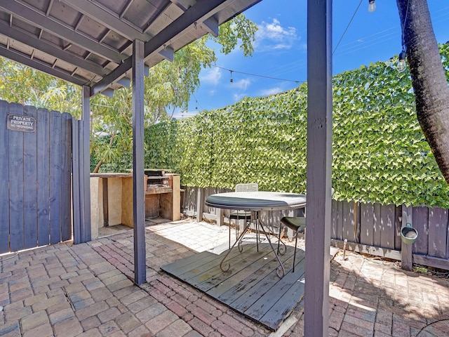 view of patio featuring outdoor dining space, a deck, and fence
