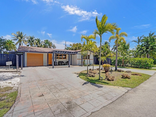 view of front of house featuring fence, a tiled roof, a garage, stucco siding, and curved driveway