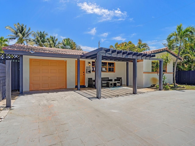 view of front of house with a tile roof, stucco siding, fence, a pergola, and a garage