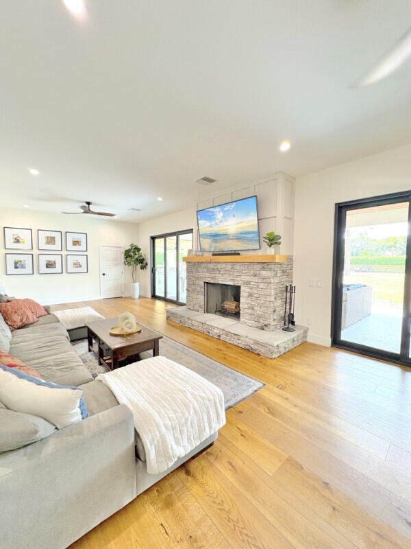 9600 Payton Ct, Boynton Beach, FL 33472 - living room with light wood-type flooring, a fireplace with raised hearth, ceiling fan, recessed lighting, and baseboards
