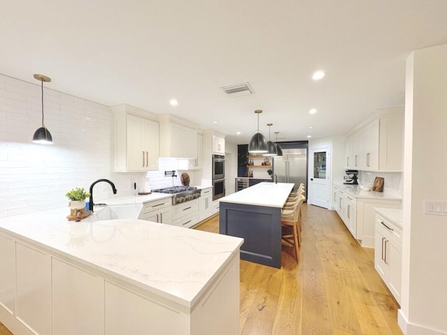 9600 Payton Ct, Boynton Beach, FL 33472 - kitchen with a sink, a peninsula, appliances with stainless steel finishes, tasteful backsplash, and light wood-style floors