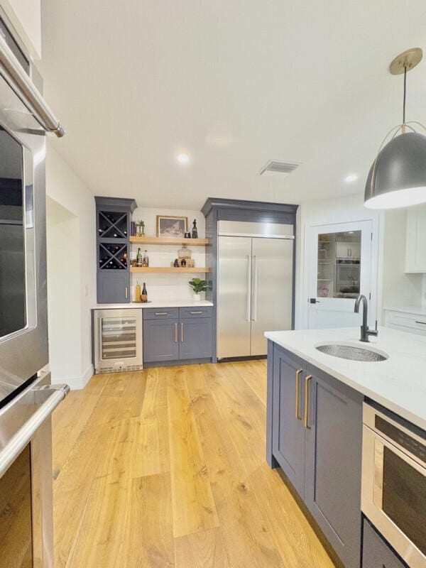 9600 Payton Ct, Boynton Beach, FL 33472 - kitchen featuring appliances with stainless steel finishes, wine cooler, a sink, gray cabinetry, and light countertops