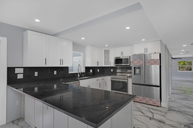 6008 S Citrus Ave, Fort Pierce, FL 34982 - kitchen with appliances with stainless steel finishes, light marble finish flooring, a peninsula, decorative backsplash, and dark stone counters