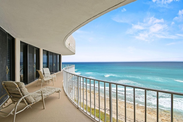 balcony with a water view and a view of the beach