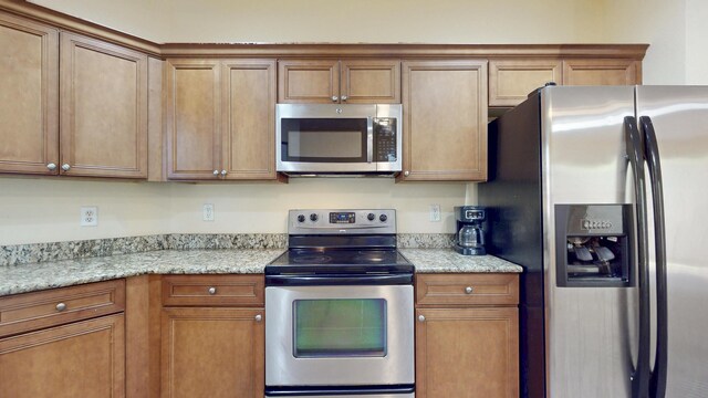 2558 SE Pineland Dr, Port Saint Lucie, FL 34952 - kitchen with stainless steel appliances, brown cabinets, and light stone counters
