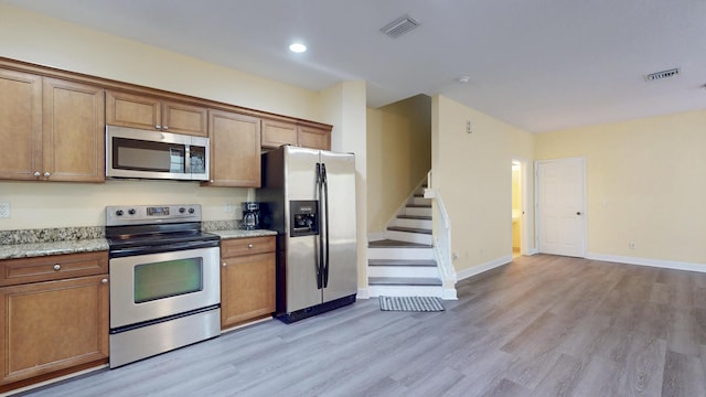 2558 SE Pineland Dr, Port Saint Lucie, FL 34952 - kitchen with light wood-style flooring, brown cabinets, appliances with stainless steel finishes, and visible vents