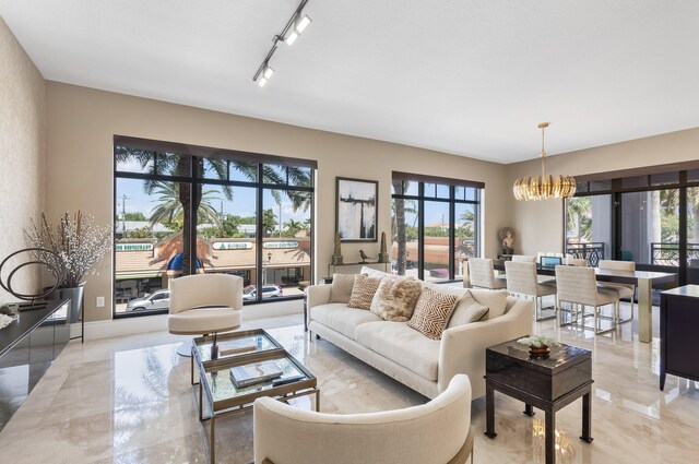 living room with rail lighting, marble finish floor, and a notable chandelier