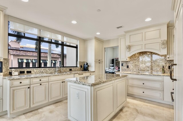 kitchen with cream cabinetry, decorative backsplash, and a sink