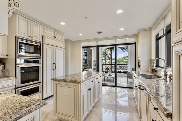 kitchen featuring a sink, built in appliances, marble finish floor, and cream cabinetry