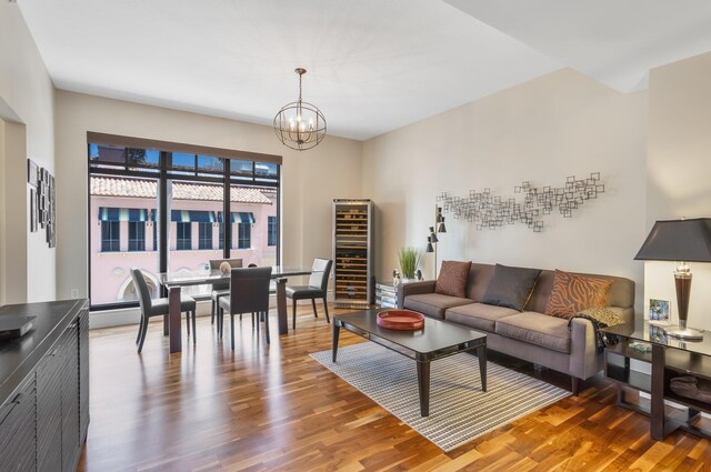 living area featuring wine cooler, wood finished floors, and a notable chandelier