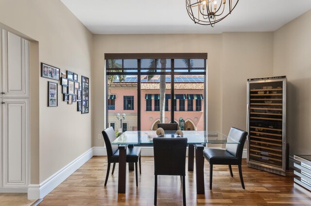 dining room featuring light wood-style floors, baseboards, beverage cooler, and a chandelier