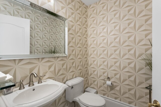 bathroom with a sink, toilet, and tile walls