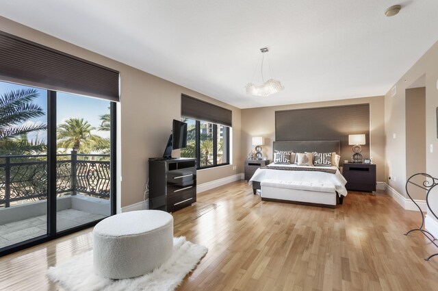 bedroom featuring baseboards, light wood-style flooring, a chandelier, and access to exterior