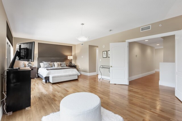 bedroom featuring baseboards, light wood-style flooring, and visible vents