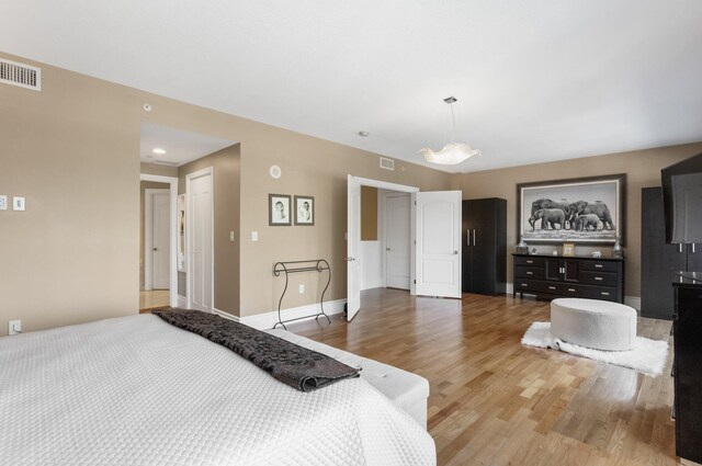 bedroom featuring baseboards, visible vents, and light wood finished floors