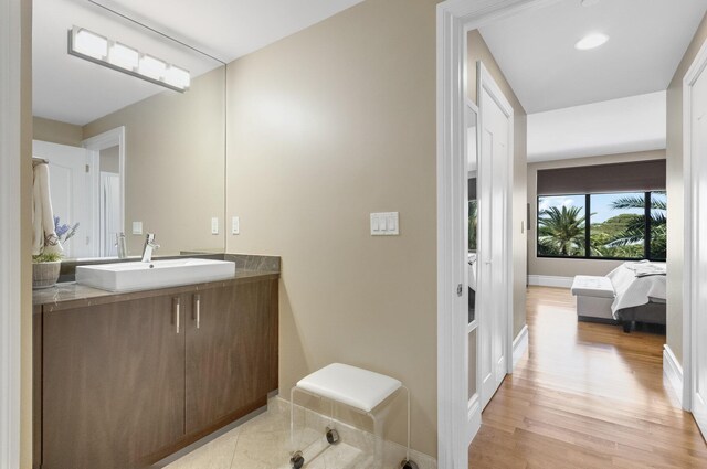 bathroom with baseboards, wood finished floors, and vanity