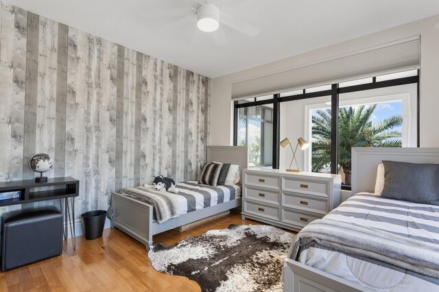 bedroom featuring ceiling fan, wood finished floors, and an accent wall