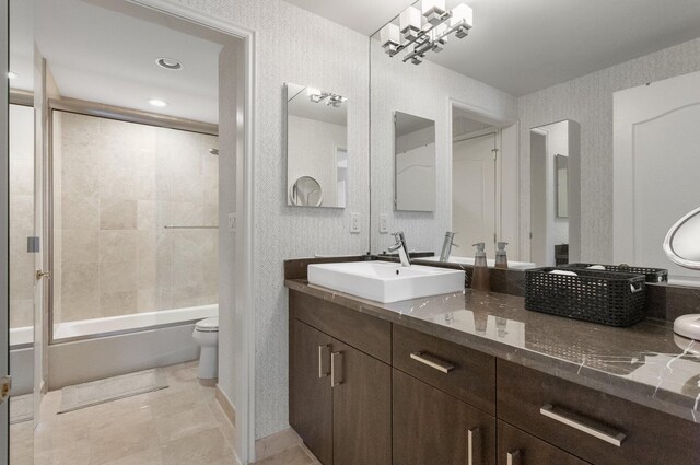 bathroom with toilet, combined bath / shower with glass door, tile patterned flooring, and vanity