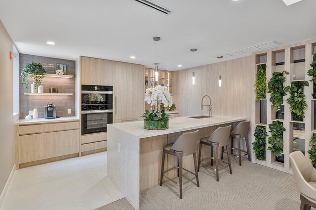 kitchen with a sink, light brown cabinetry, multiple ovens, and open shelves