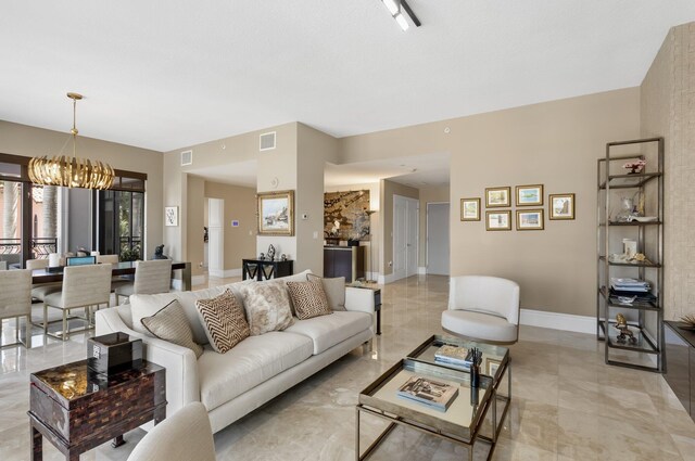 living room featuring baseboards, a chandelier, and visible vents