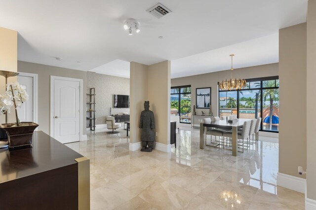 interior space featuring marble finish floor, baseboards, a notable chandelier, and visible vents
