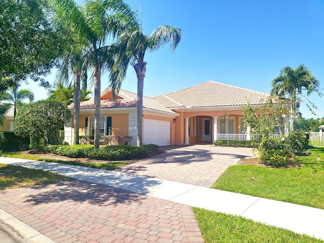 10902 SW Blue Mesa Way, Port Saint Lucie, FL 34987 - view of front of house featuring a garage, stucco siding, a porch, decorative driveway, and a tiled roof
