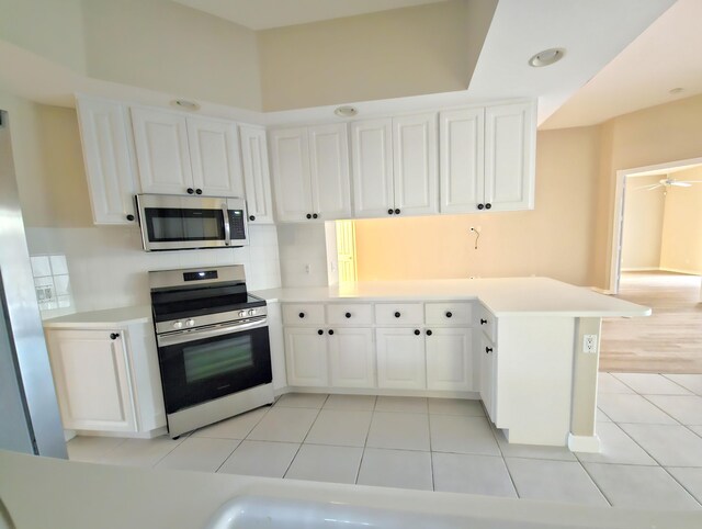 10902 SW Blue Mesa Way, Port Saint Lucie, FL 34987 - kitchen with stainless steel appliances, a peninsula, white cabinets, light tile patterned floors, and light countertops