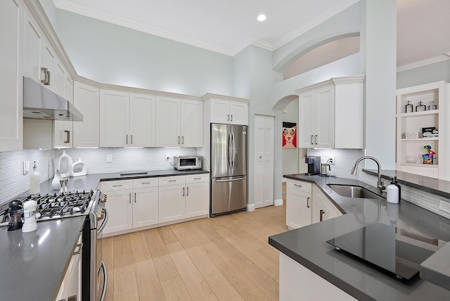 10740 Grande Blvd, West Palm Beach, FL 33412 - kitchen featuring dark countertops, appliances with stainless steel finishes, arched walkways, under cabinet range hood, and a sink