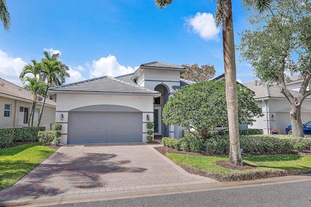 10740 Grande Blvd, West Palm Beach, FL 33412 - view of front facade featuring a tiled roof, a garage, decorative driveway, and stucco siding